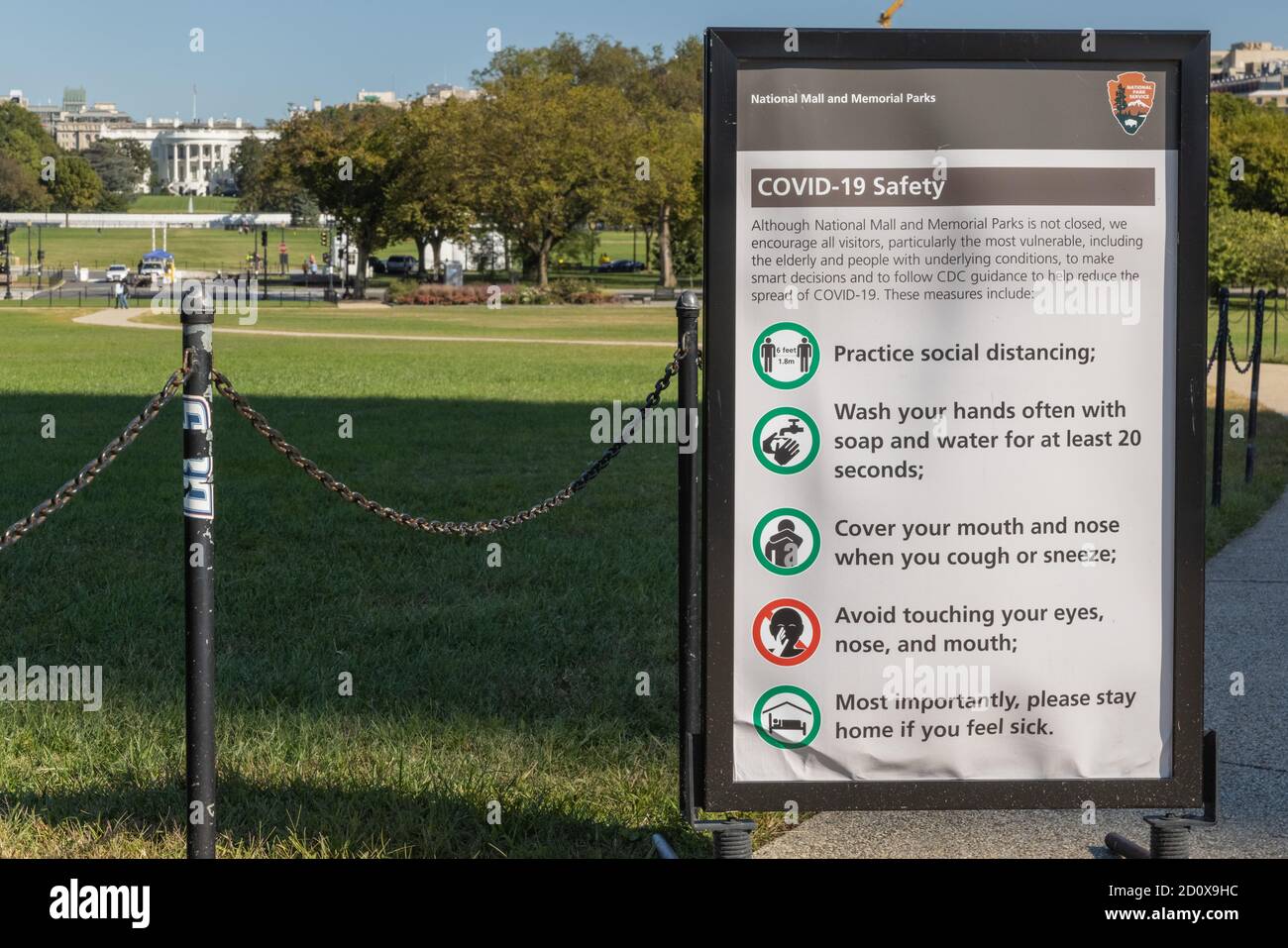 Poster con le istruzioni di sicurezza Covid-19 sul National Mall vicino al Washington Monument con la Casa Bianca oltre Foto Stock