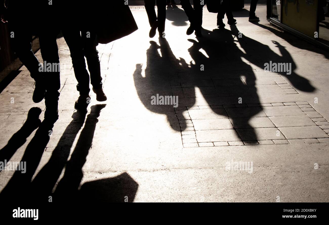 La silhouette dell'ombra sfocata di persone che camminano sulla strada pedonale dentro seppia nero e bianco ad alto contrasto Foto Stock