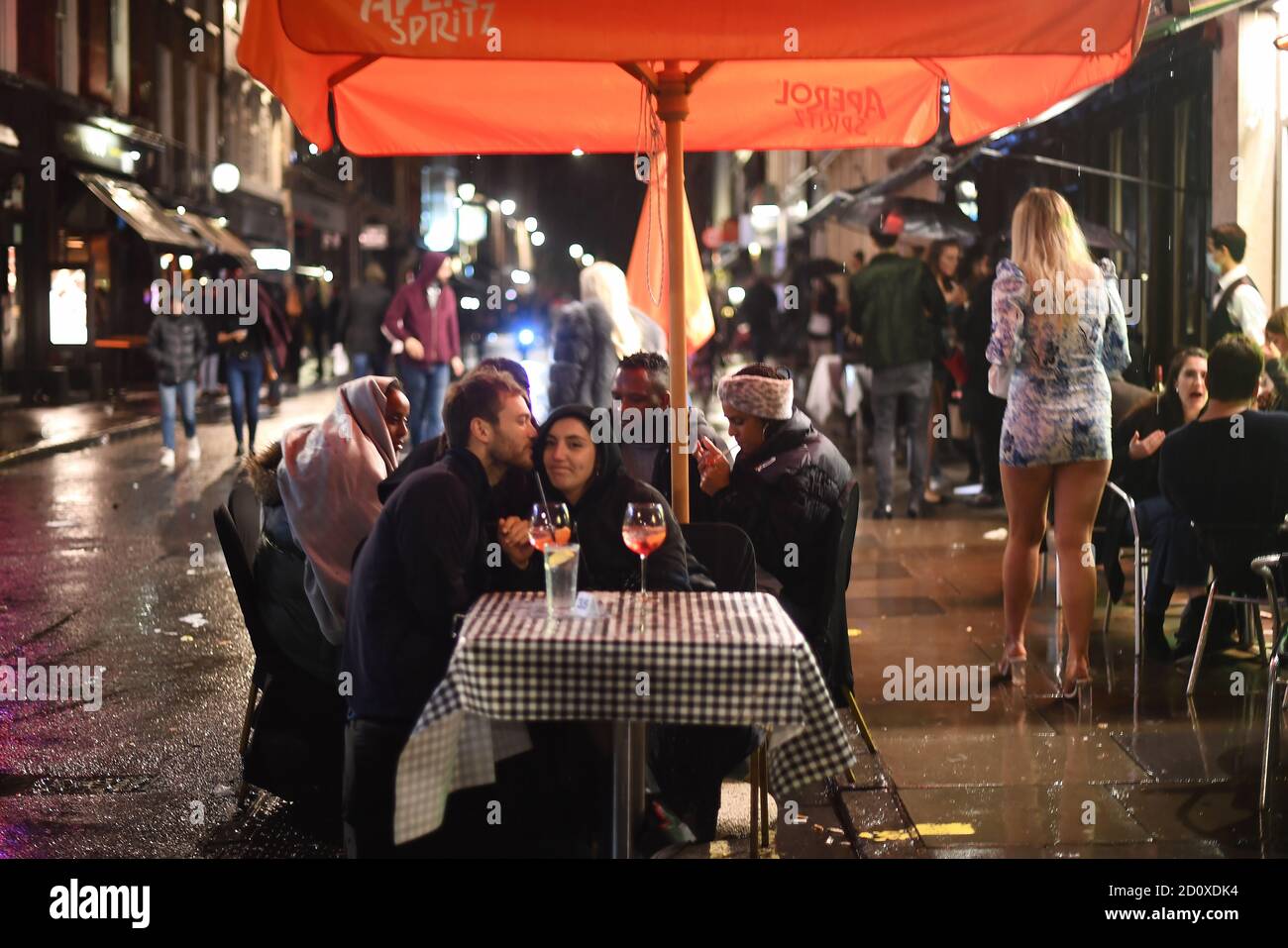Le persone che bevono all'esterno di un bar a Soho, Londra, davanti ai pub e ristoranti del coprifuoco alle 22:00 sono soggette a per combattere l'aumento dei casi di coronavirus in Inghilterra. Foto Stock