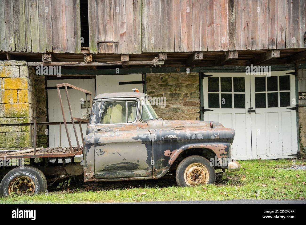 Berks County, Pennsylvania, 21 settembre 2020: Vecchio camion GMC arrugginito parcheggiato sotto il granaio rosso rustico Foto Stock