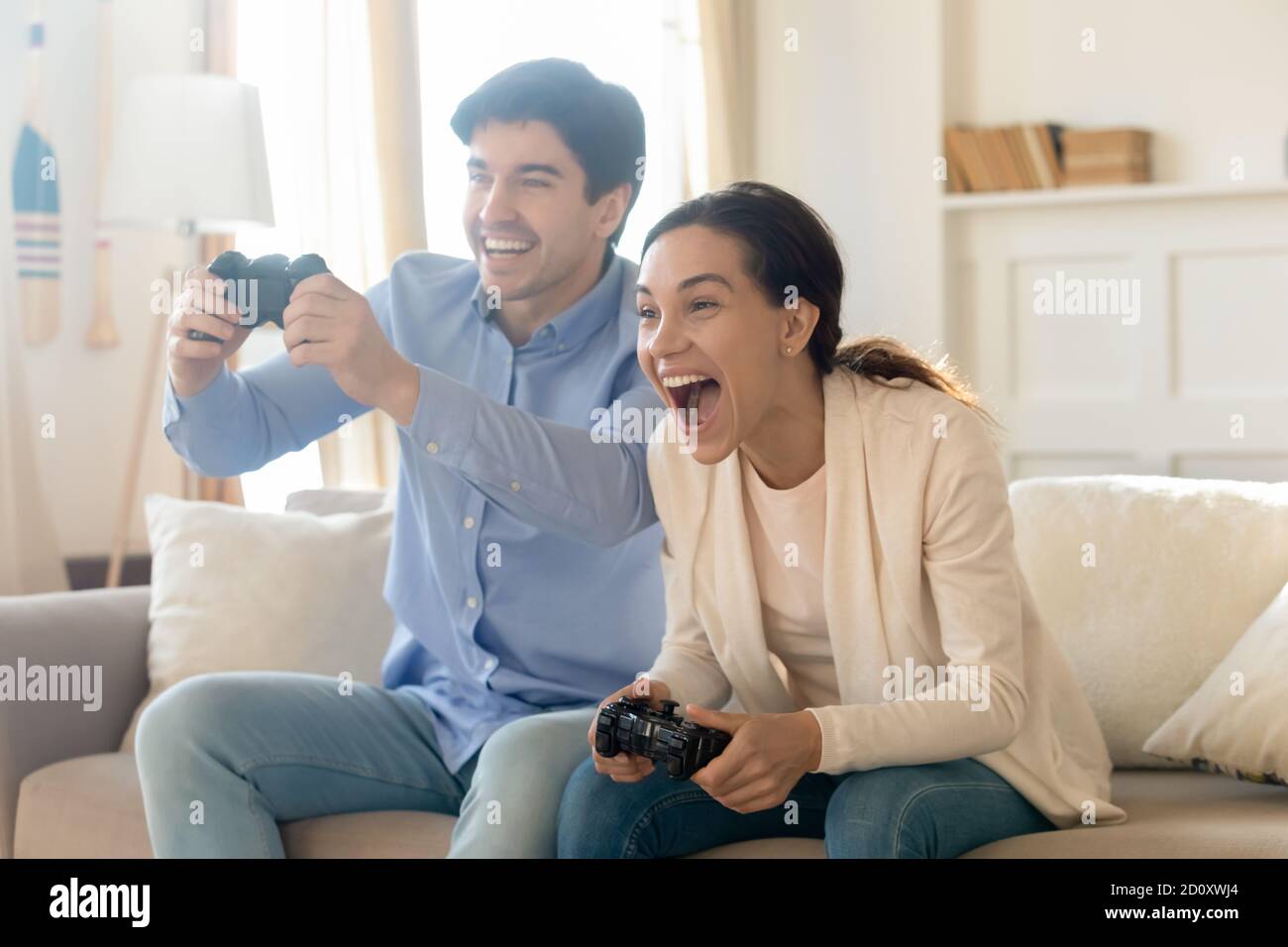 Emozionale giovane famiglia sposata coppia giocando console videogiochi Foto Stock