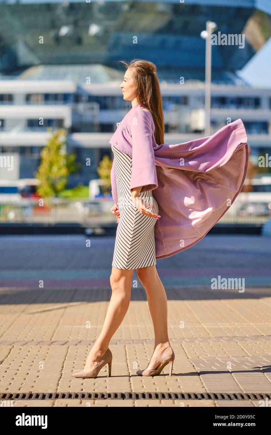 Donna trendy in abito a righe getta aperto cappotto lilla all'aperto Foto  stock - Alamy