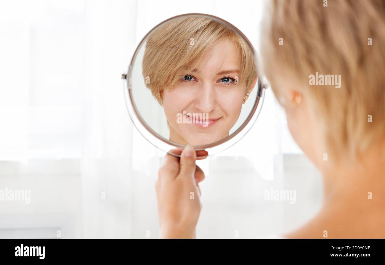 Bella giovane donna sana che guarda nello specchio nel mattina Foto Stock