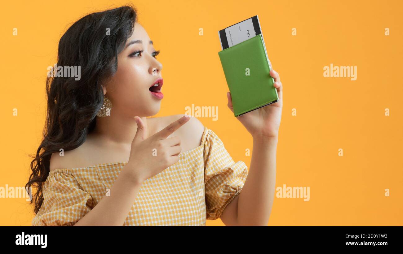 È tempo di viaggiare. Una donna moderna e alla moda sorridente in abiti casual con biglietti aerei e un passaporto in mano. Foto Stock