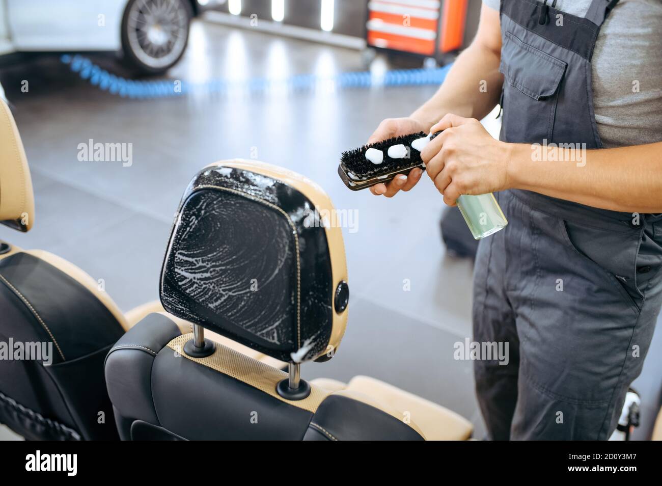 Il lavoratore applica l'agente sulla spazzola, sui dettagli dell'auto Foto Stock