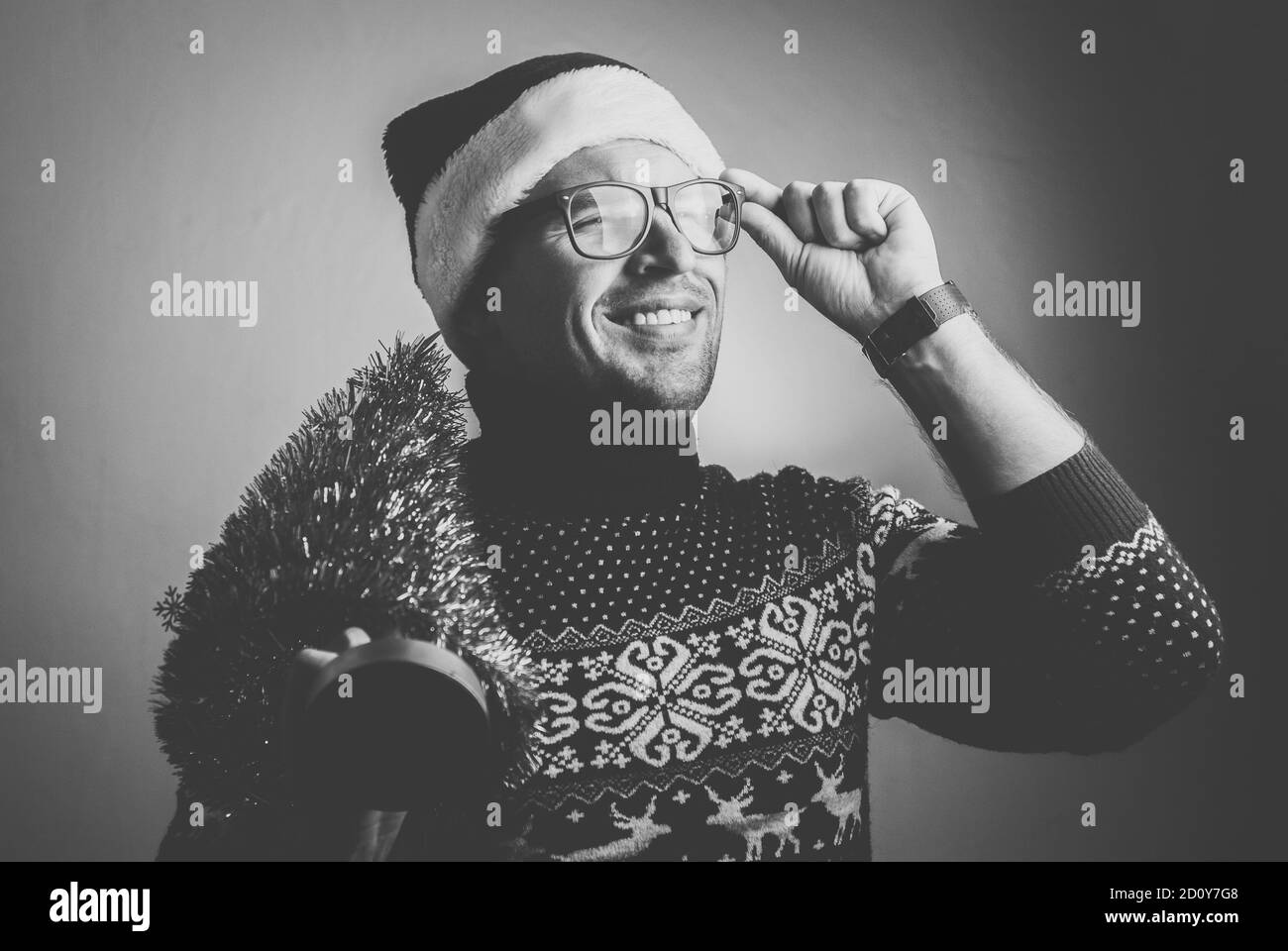 Giovane uomo in abiti natalizi con un piccolo albero di Natale, foto in bianco e nero, Foto Stock