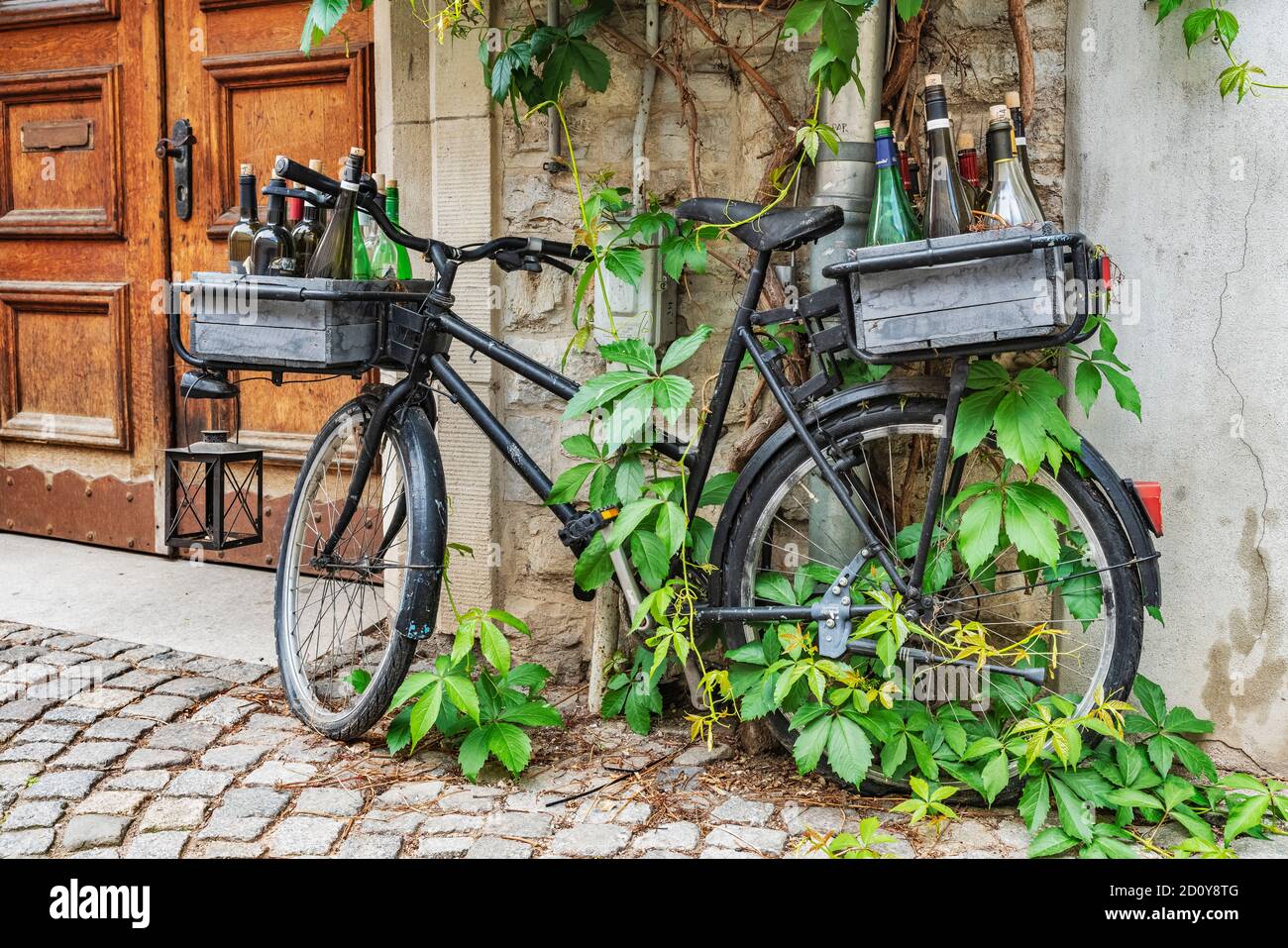 Una bicicletta nera si appoggia contro un muro di una casa. Ci sono bottiglie vuote nei cestini, Erfurt, Turingia, Germania, Europa Foto Stock