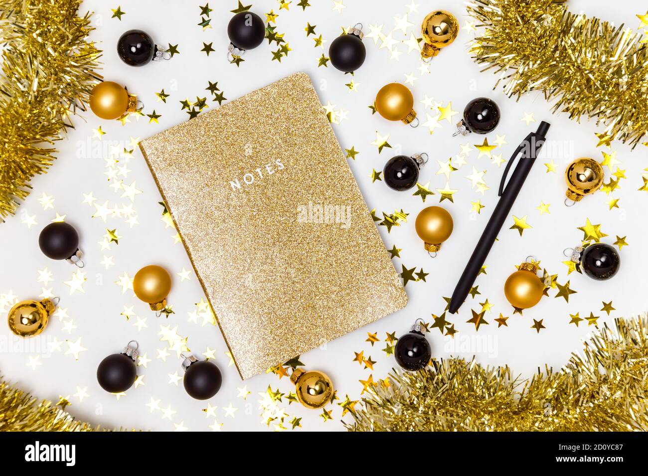 Taccuino d'oro con brillante copertina glitter, baubles natalizi in oro e nero, stelle garland e confetti. Saldo annuale, lista dei desideri, risoluzioni per i nuovi anni Foto Stock