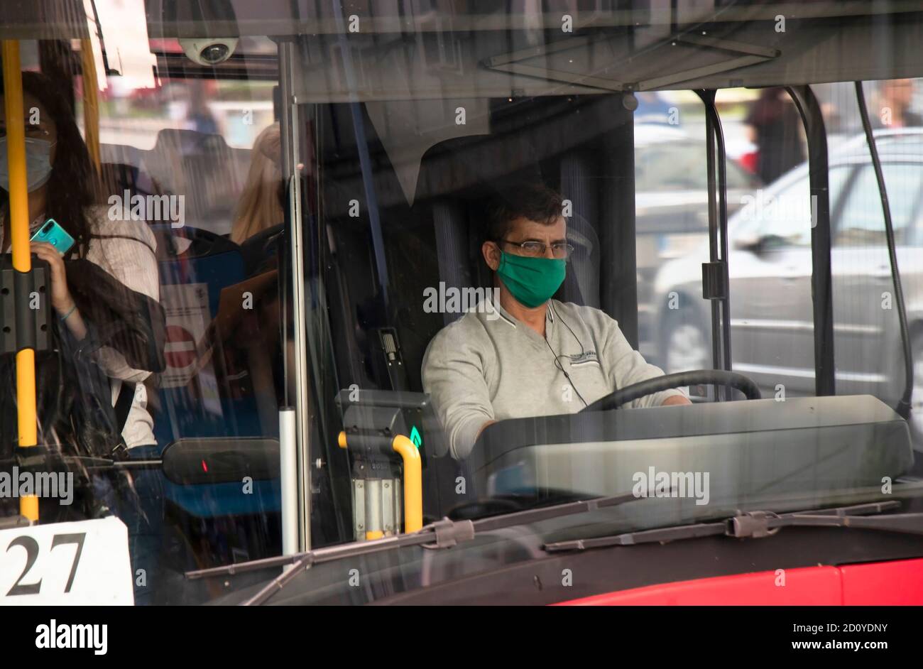 Belgrado, Serbia - 02 ottobre 2020: Conducente che indossa una maschera chirurgica facciale che guida un autobus cittadino con passeggeri, dall'esterno attraverso il vetro anteriore Foto Stock