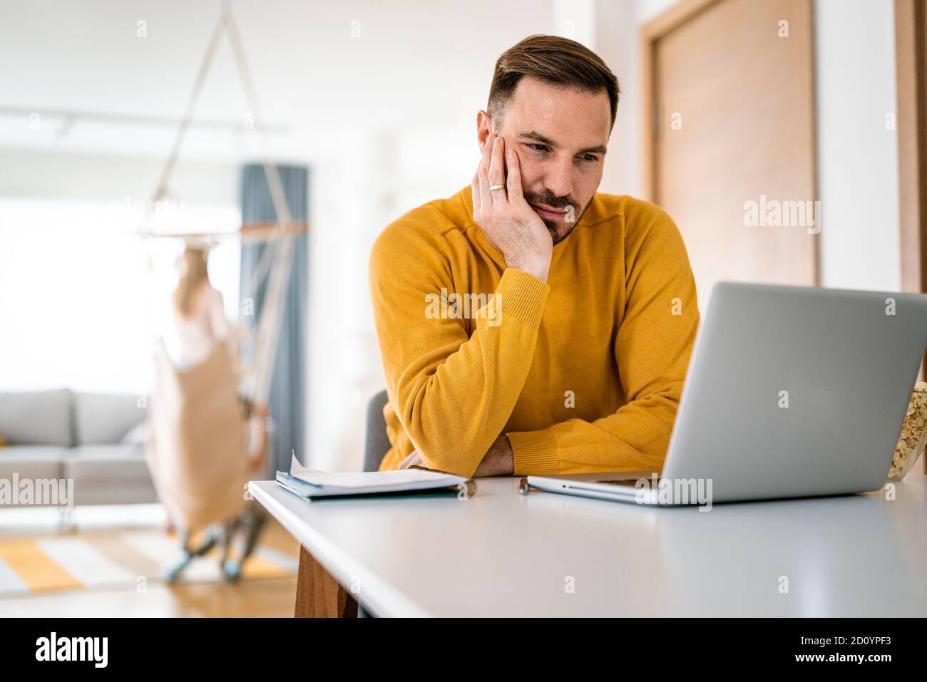 Sconvolto giovane uomo conta budget familiare su laptop Foto Stock