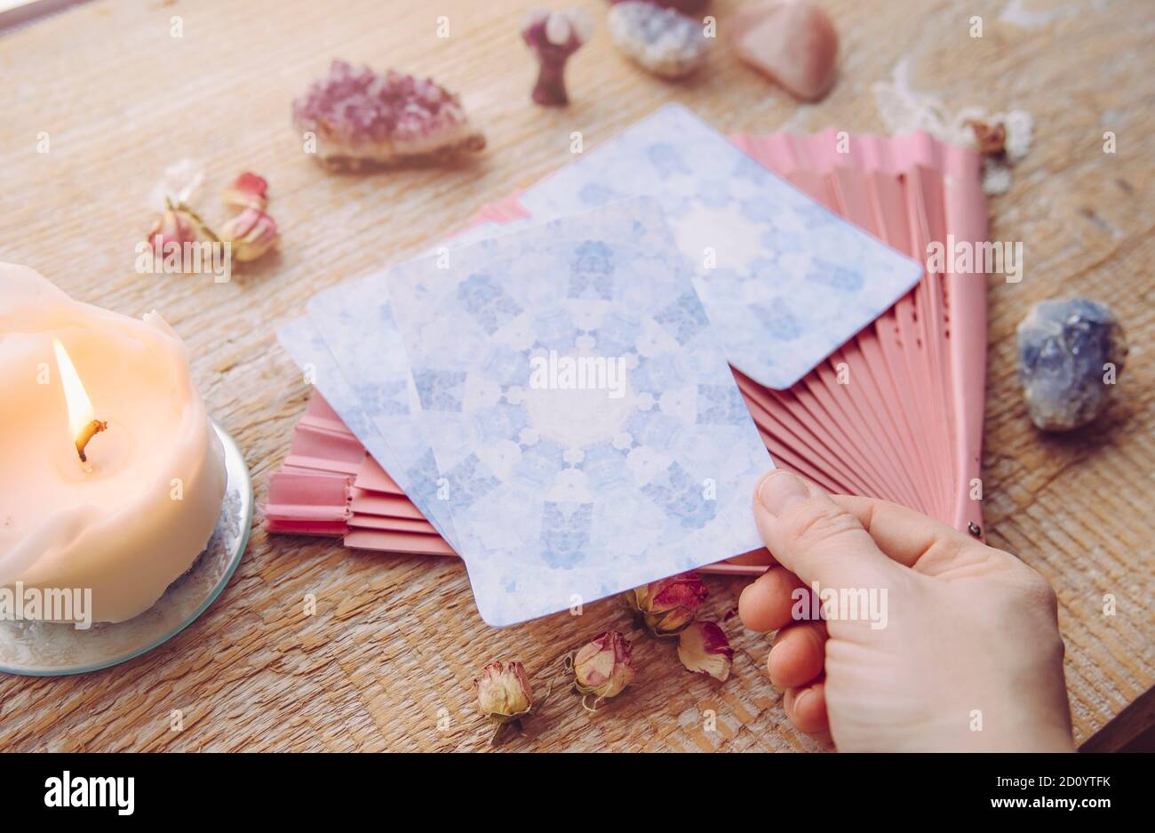 Ponte con divinazione carte Angelo fatte in casa su tavolo di legno, circondato da pietre semi-preziose cristalli e candele. Persona che sceglie una carta. Foto Stock