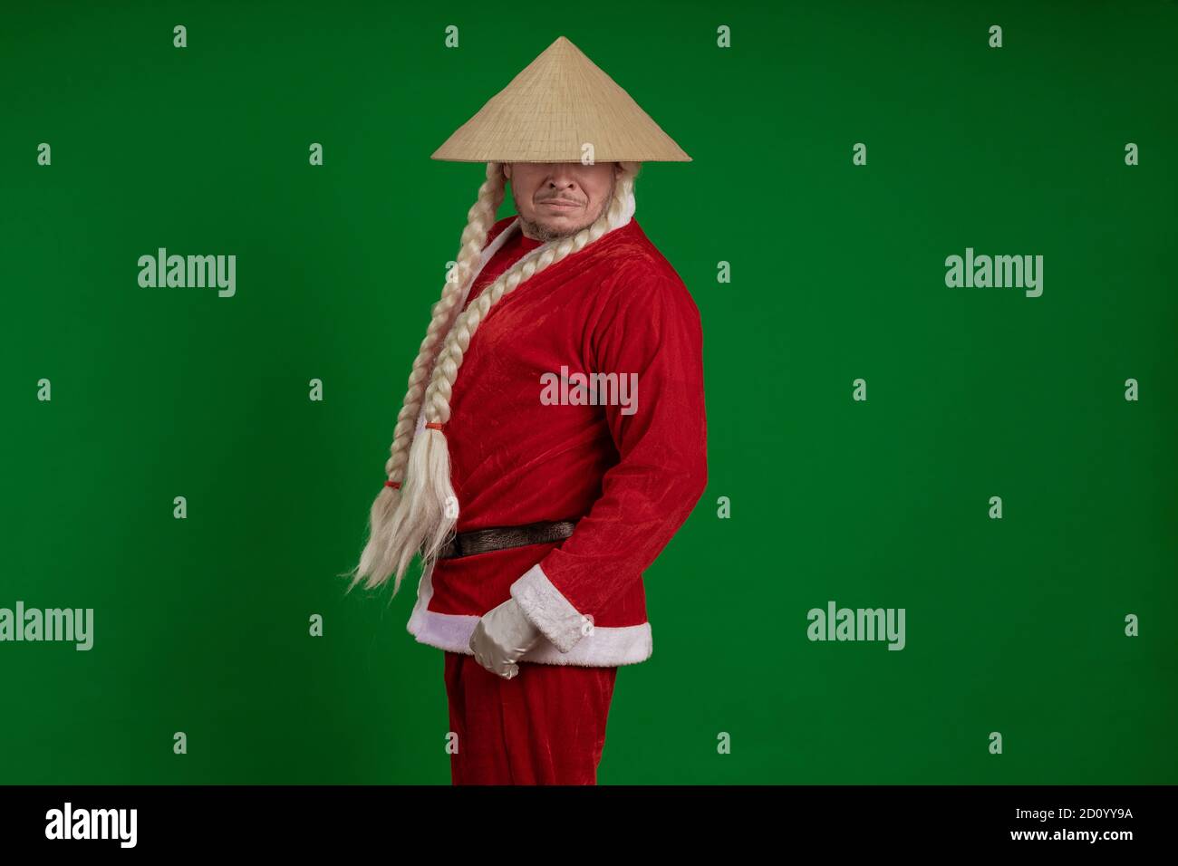 Attore maschile vestito come Babbo Natale con lunghe trecce acconciatura E  cappello asiatico in posa su sfondo verde cromato Foto stock - Alamy