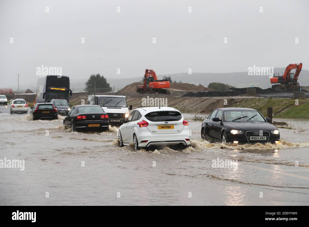 Le auto si fanno strada attraverso una strada allagata a Claudy, contea di Londonderry. Il weekend sul bagnato del Regno Unito continuerà poiché è stato esteso un avvertimento meteo per la pioggia in varie parti del Galles e dell'Inghilterra. Foto Stock