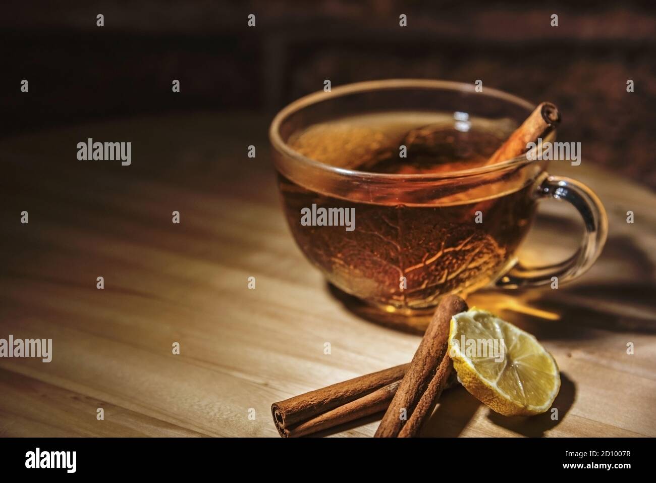 Una tazza di tè con bastoncini di cannella e una fetta di limone su un tavolo di legno, primo piano, isolato Foto Stock