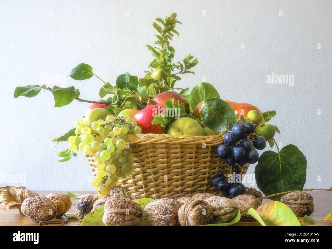 Concetto di natura autunnale, splendido assortimento di frutta in un cesto su un tavolo di legno. Composizione di una varietà di frutti organici crudi. Foto Stock