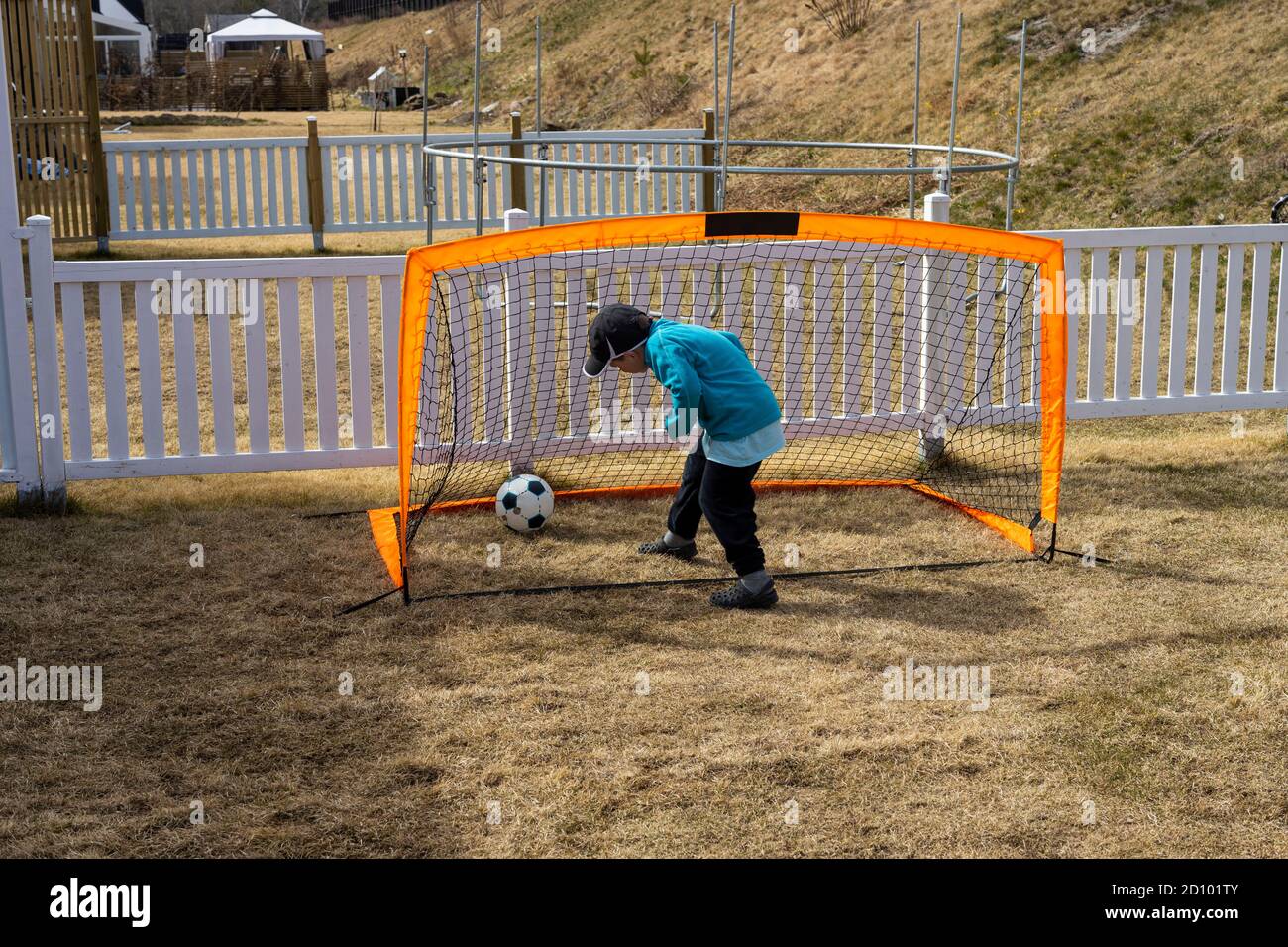 Rimani a casa. COVID 19. Vista ravvicinata del ragazzo che gioca a calcio sul cortile. Concetto di giochi all'aperto. Foto Stock