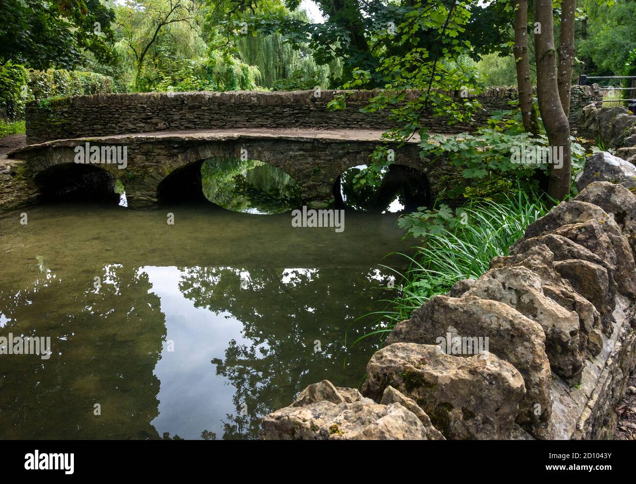 Un ponte pedonale sul fiume a Castle Combe, Wiltshire, Regno Unito Foto Stock