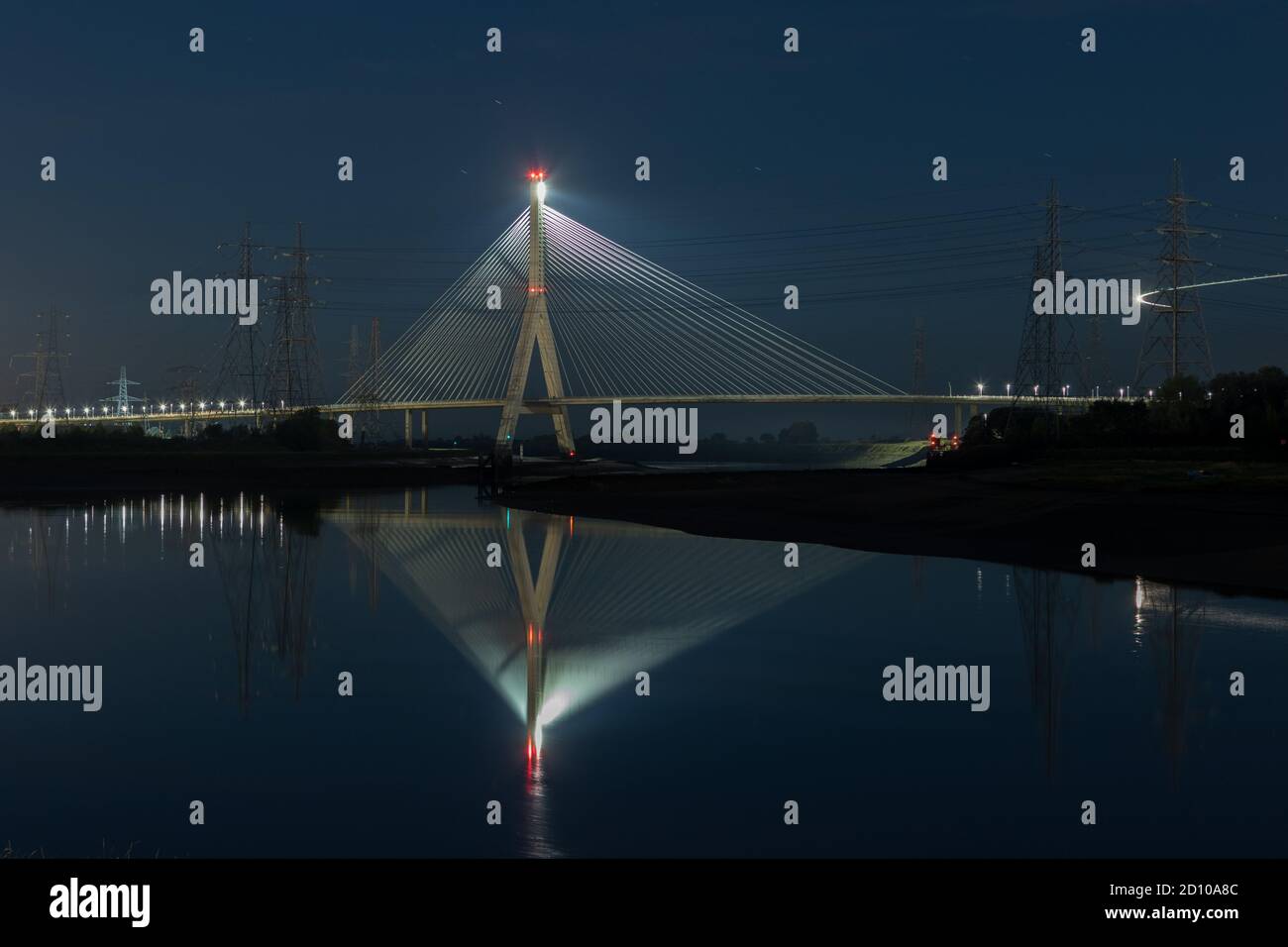Il ponte in cemento Flintshire, illuminato di notte, attraversa il fiume Dee e si affaccia sul Quay di Connah. Struttura simile a quella di una ventola riflessa nell'estuario specchiato Foto Stock
