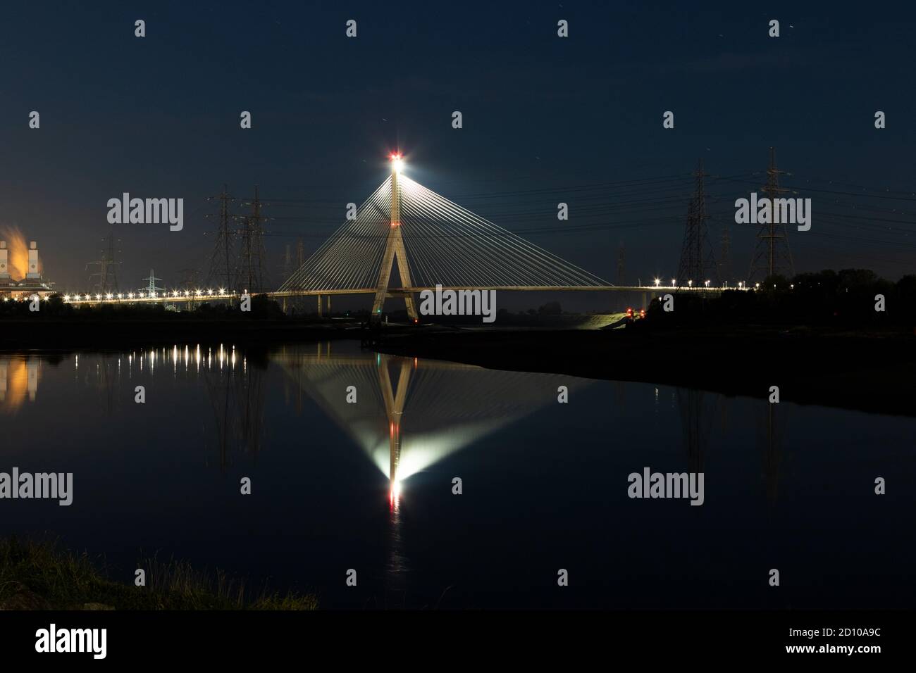 Il ponte in cemento Flintshire, illuminato di notte, attraversa il fiume Dee e si affaccia sul Quay di Connah. Struttura simile a quella di una ventola riflessa nell'estuario specchiato Foto Stock