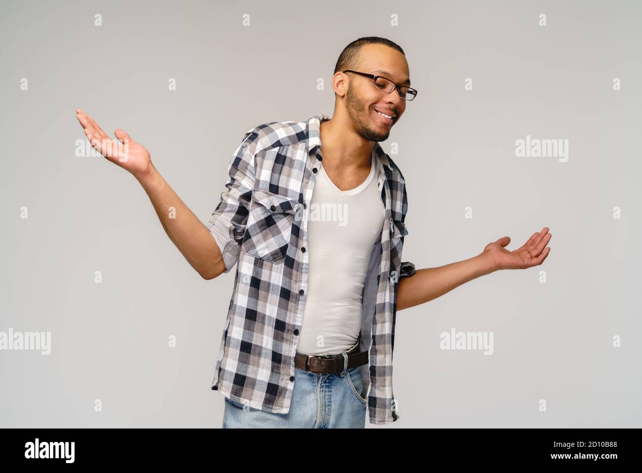 Non conosco il gesto - giovane afrciano americano uomo su sfondo grigio essere a perdita, mostrando un gesto impotente con braccio e mani, come se non lo fa Foto Stock
