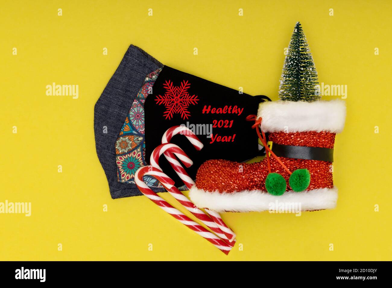 Panno cotone maschera riutilizzabile viso con testo sano 2021 Capodanno e decorazione di Natale su sfondo giallo. Foto Stock