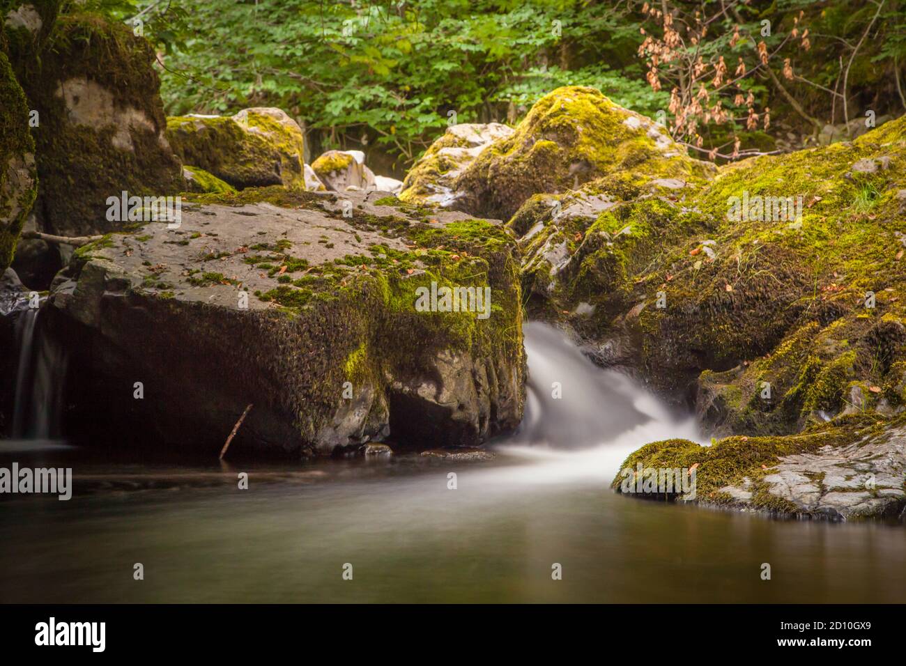 Acqua che scorre lungo le cascate di Aira Force, un sito del National Trust nel Lake District, Inghilterra, acquisita con una lunga esposizione. Foto Stock
