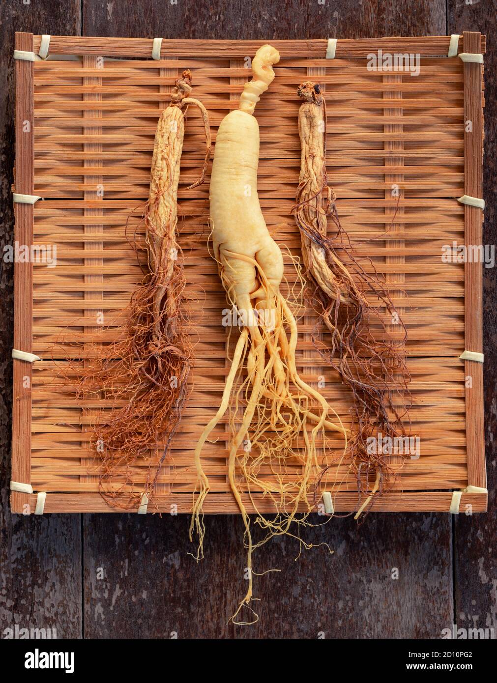 Ginseng fresco e asciutto su tessitura di bambù con spazio di copia sullo sfondo di legno Foto Stock