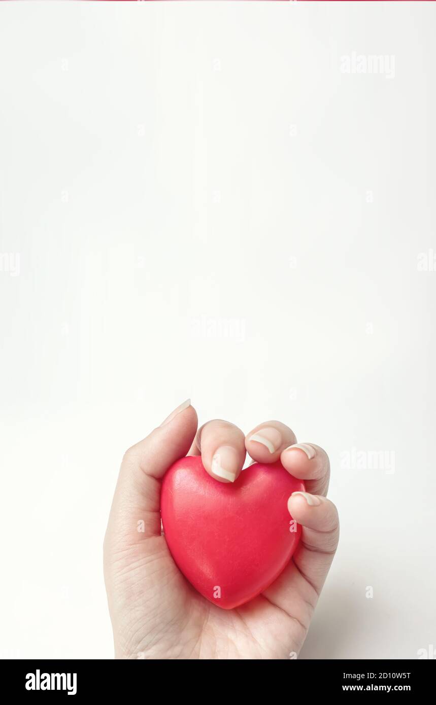 Tenere la mano con il cuore rosso. Concetto di CSR, giornata mondiale del cuore, giornata mondiale della salute, giornata nazionale dei donatori di organi Foto Stock