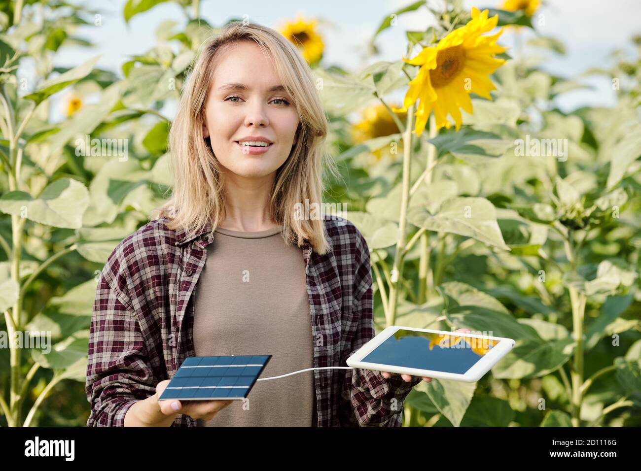 Felice giovane femmina che tiene il tablet digitale collegato alla batteria solare per la ricarica Foto Stock