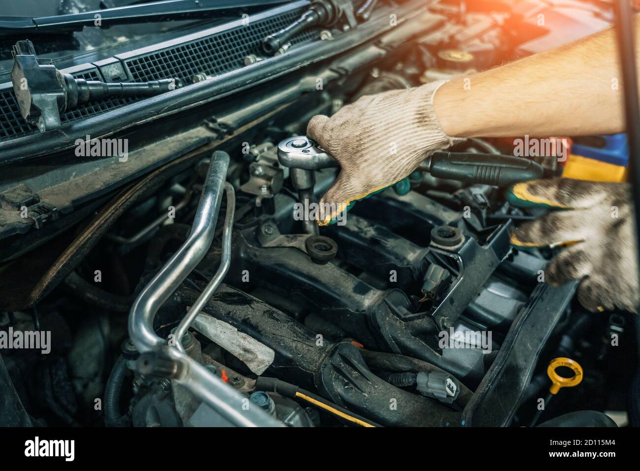Le mani del lavoratore cambiano le candele nel motore dell'automobile in servizio automatico, primo piano. Foto Stock