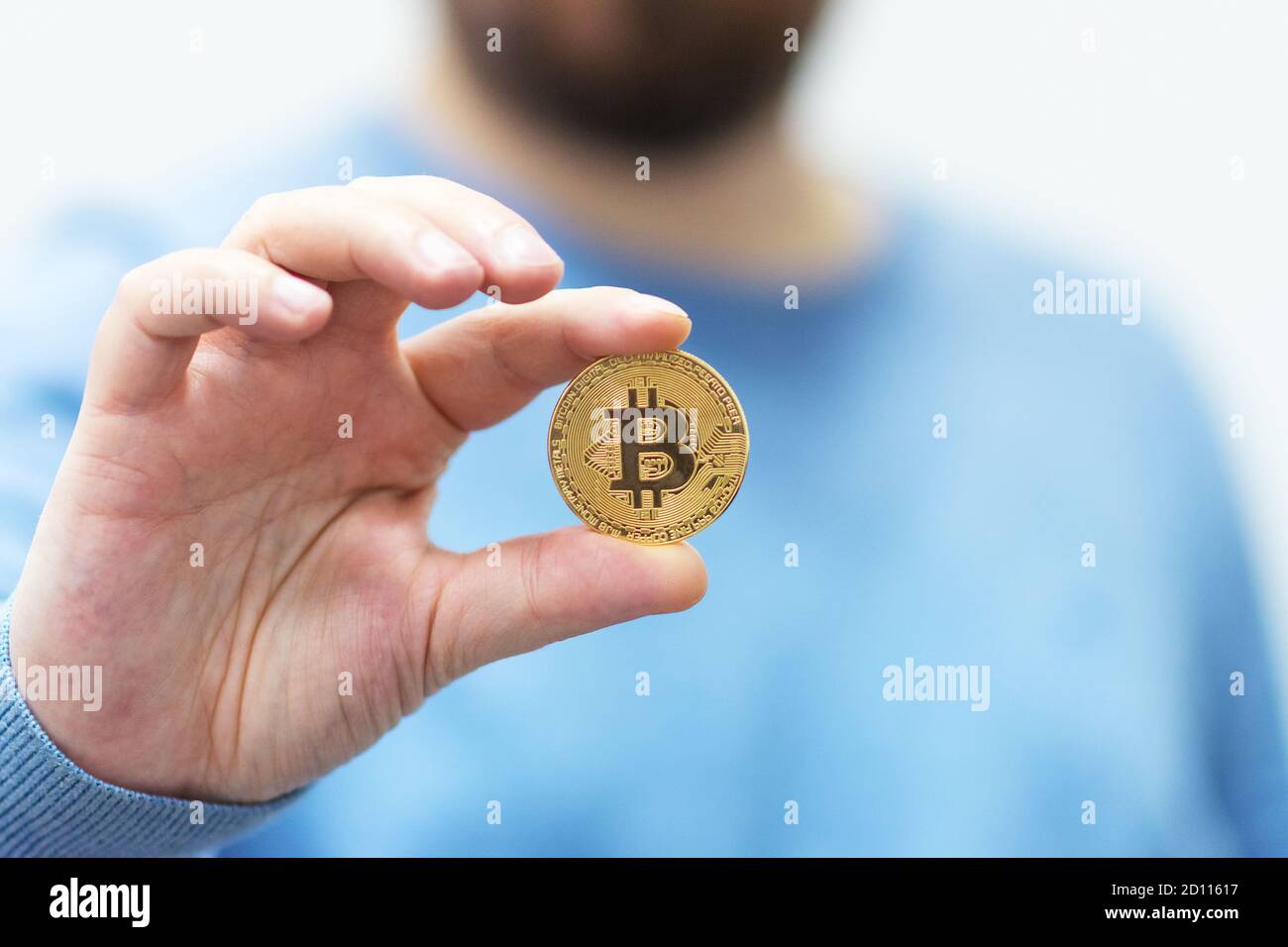 Bitcoin in su nell'aria. Uomo che mostra la criptovaluta bitcoin. Concetto di moneta criptovaluta in metallo dorato. Foto Stock