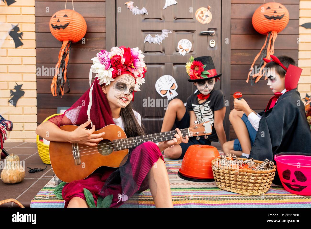 Ragazza carina in costume halloween seduta su scala, cantando e suonando la chitarra Foto Stock
