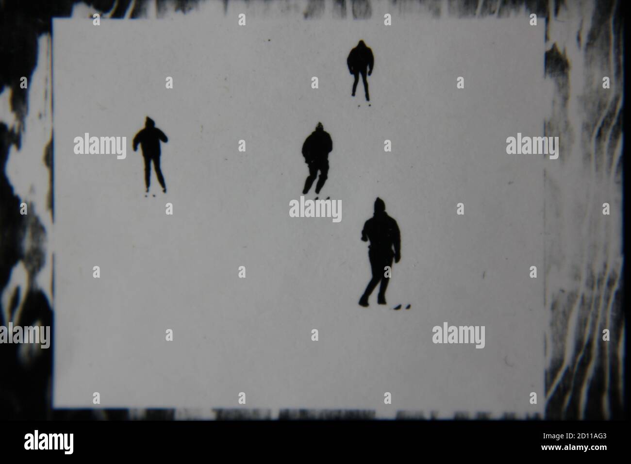 Fine anni '70 vintage profilo in bianco e nero fotografia di sciatori sulla collina di sci nei loro completi abiti da sci e sci che scende la collina. Foto Stock