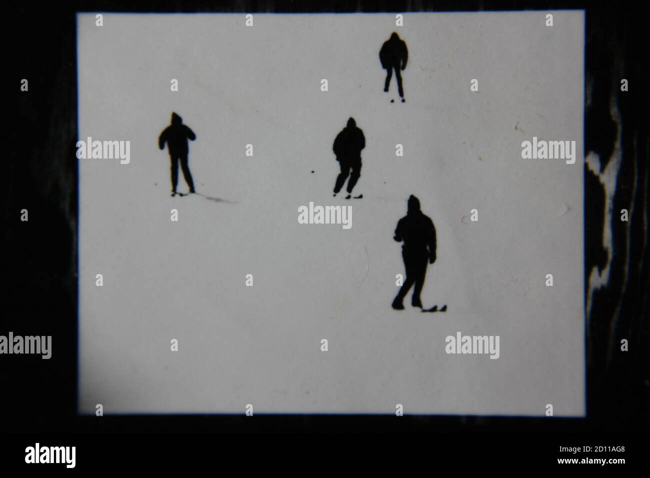 Fine anni '70 vintage profilo in bianco e nero fotografia di sciatori sulla collina di sci nei loro completi abiti da sci e sci che scende la collina. Foto Stock