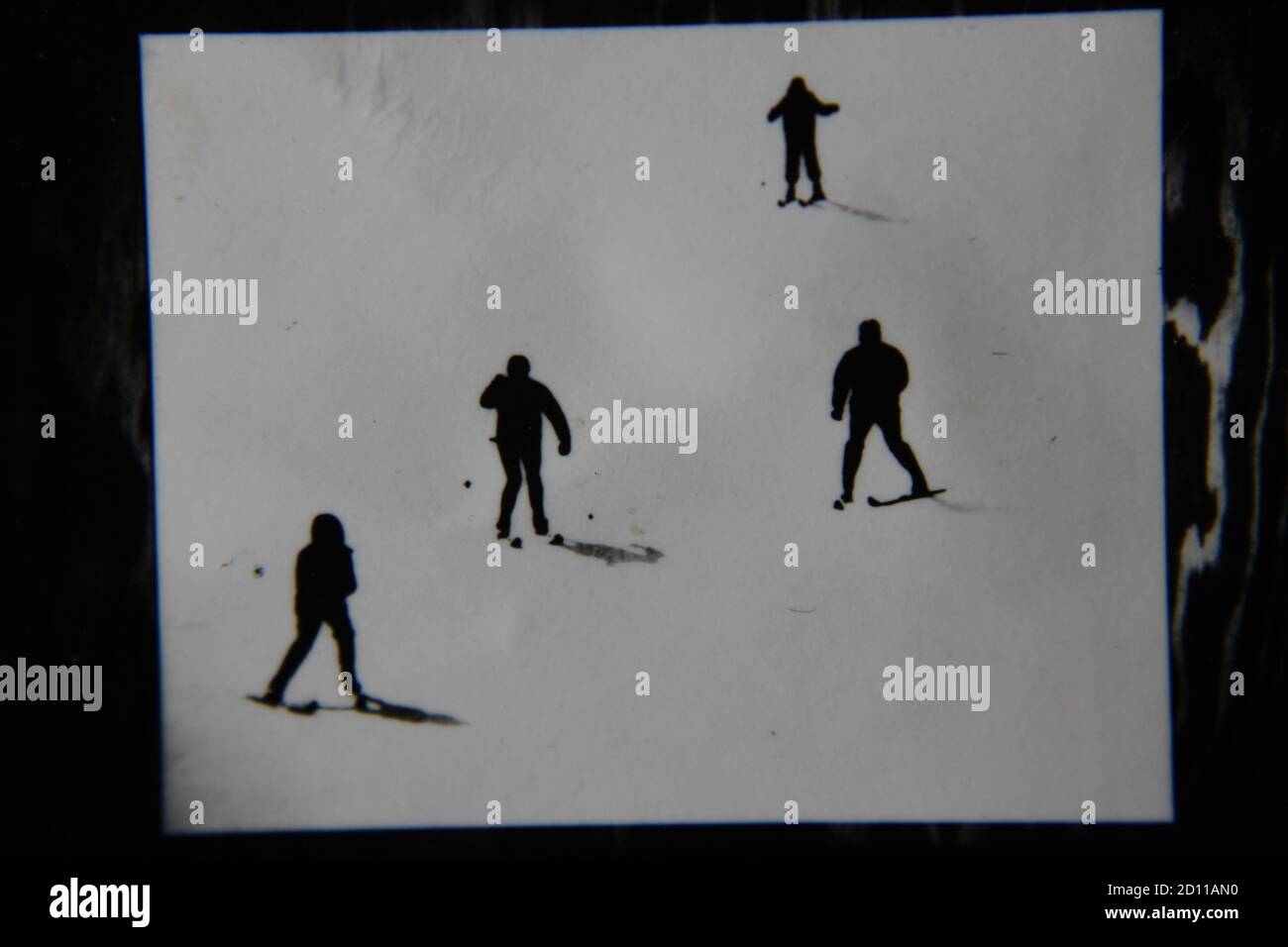 Fine anni '70 vintage profilo in bianco e nero fotografia di sciatori sulla collina di sci nei loro completi abiti da sci e sci che scende la collina. Foto Stock