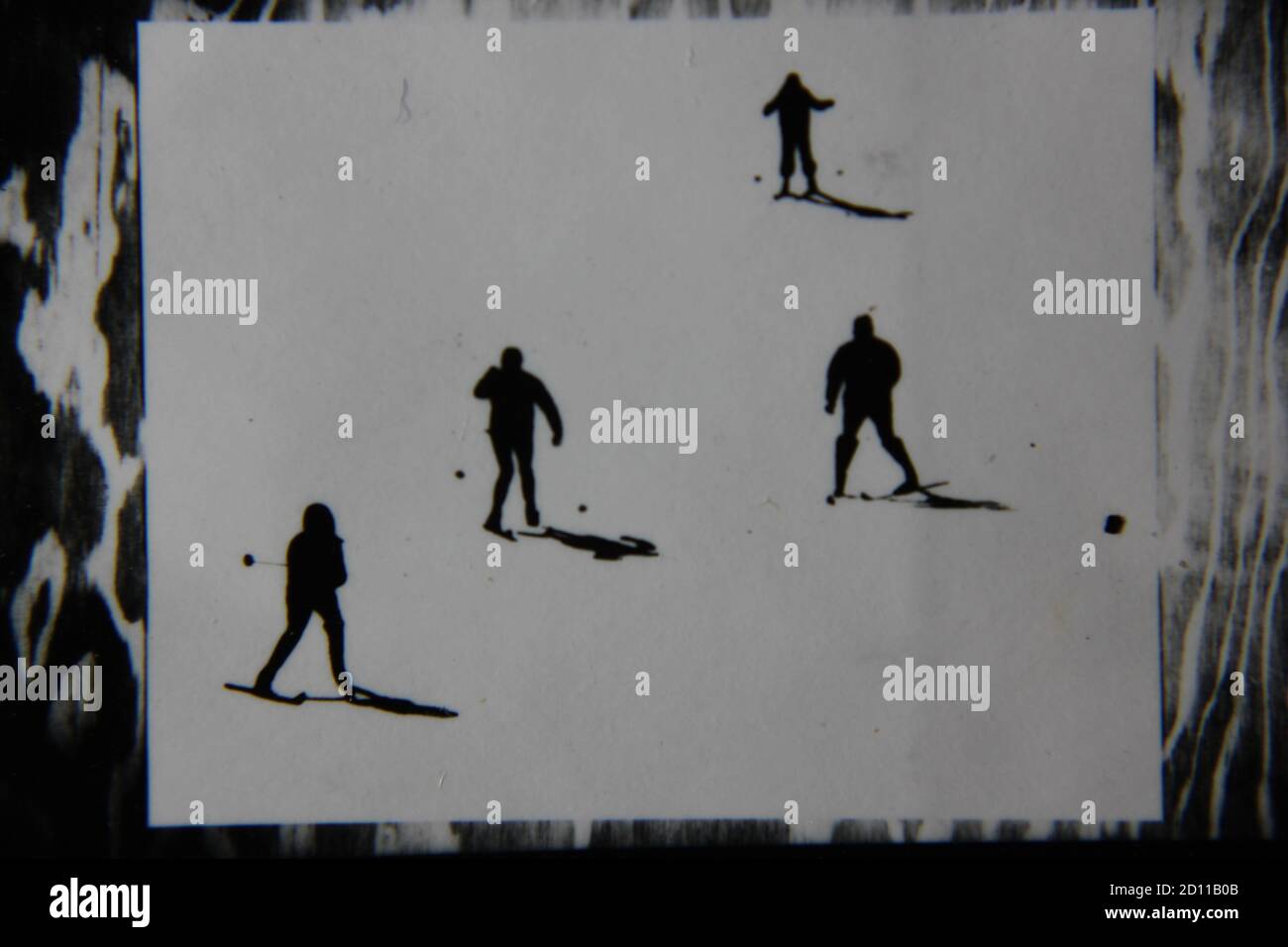 Fine anni '70 vintage profilo in bianco e nero fotografia di sciatori sulla collina di sci nei loro completi abiti da sci e sci che scende la collina. Foto Stock