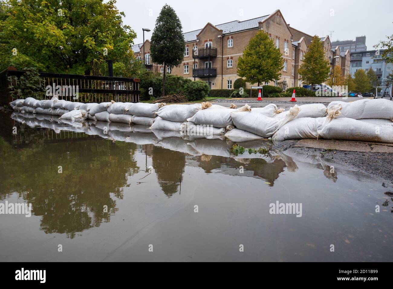 Aylesbury, Regno Unito. 4 ottobre 2020. Tempesta Alex inondazioni in Aylesbury, città della contea di Buckinghamshire. Un fine settimana di piogge quasi continue ha fatto scoppiare il Bear Brook sulle sue sponde, inondando le case di Southcourt’s Penn Road. Come la pioggia quasi continua sotparte i residenti iniziano ad accedere ai danni e iniziare a sgombrare. I servizi di emergenza erano presenti, bloccando l'accesso all'area allagata. Sacchi di sabbia messi per tenere indietro le acque alluvionali dal Bear Brook. Credito: Stephen Bell/Alamy Foto Stock