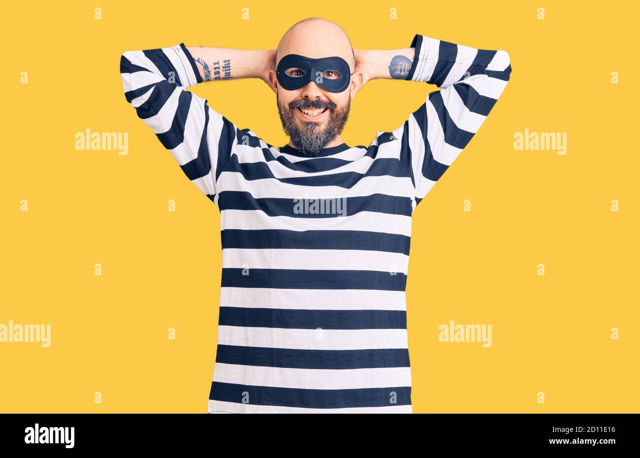 Giovane bell'uomo che indossa una maschera di scasso rilassante e stretching, braccia e mani dietro la testa e il collo sorridenti felici Foto Stock
