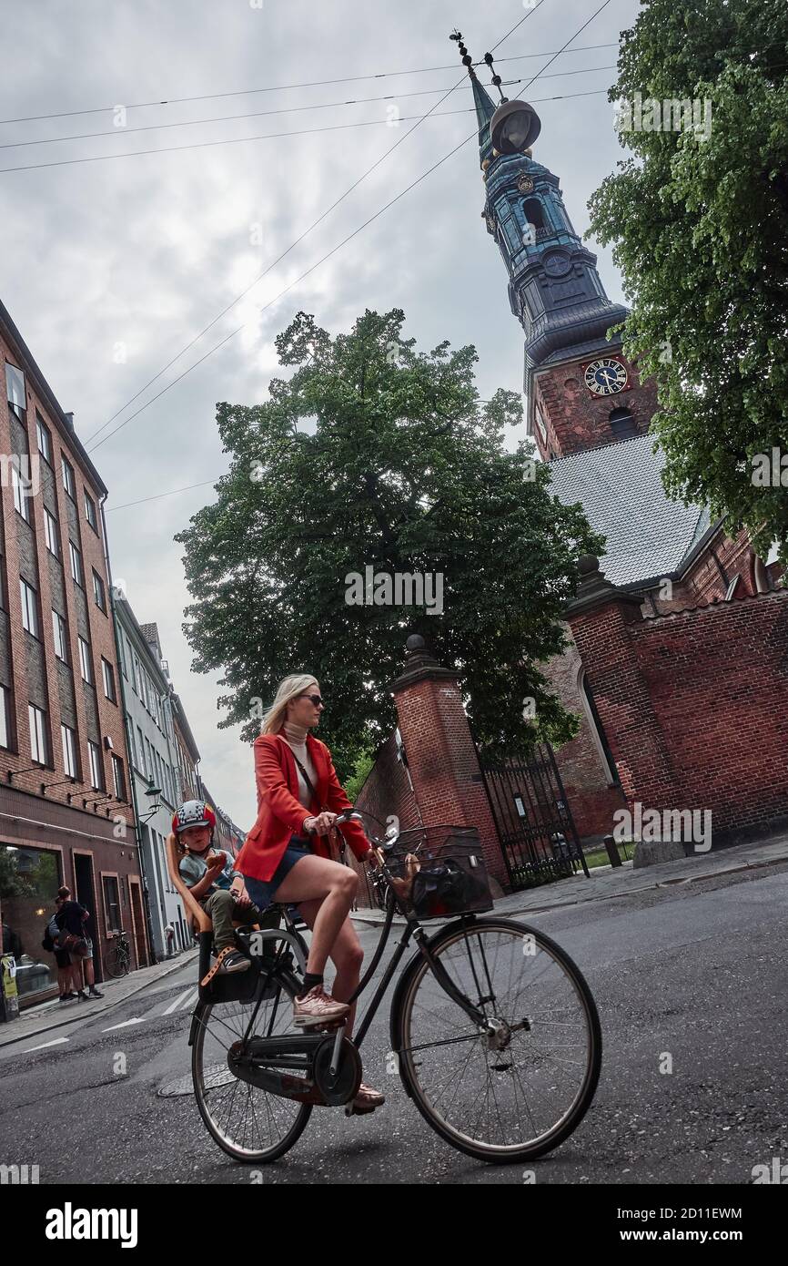 La giovane madre porta il suo bambino in bicicletta in una scena tipica della vita quotidiana scandinava, nella città di Copenhagen Foto Stock