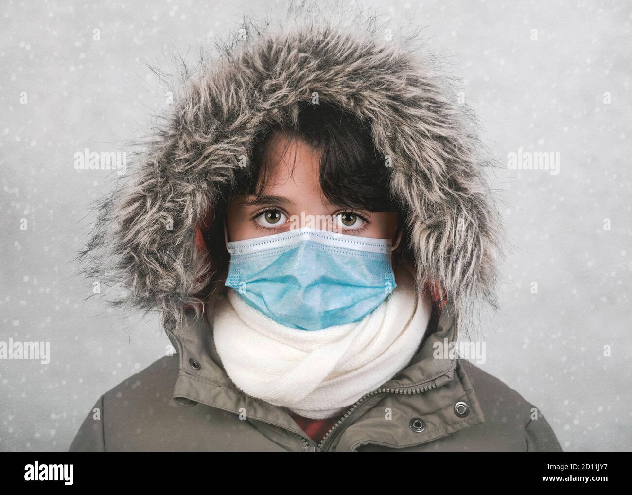 Primo piano di bambino con maschera medica che indossa cappello invernale e. sciarpa nella neve Foto Stock