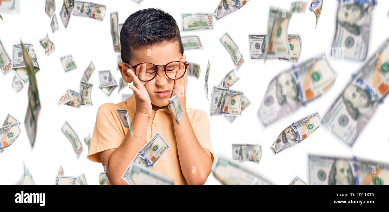 Bambino piccolo cute del ragazzo che indossa i vestiti e gli occhiali  casual che soffrono dal mal di testa disperato e stressato perché il dolore  e l'emicrania. Mani sulla testa Foto stock -