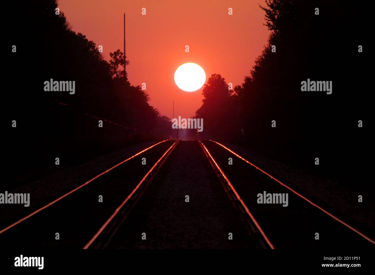Una doppia serie di binari ferroviari porta all'infinito e. un tramonto rosso fuoco Foto Stock