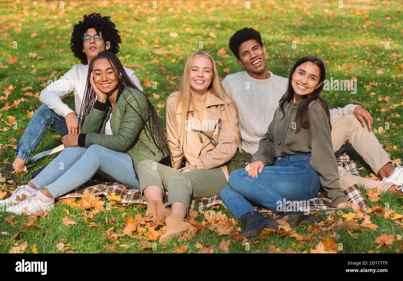 Spensierati teen amici seduti a terra al parco pubblico Foto Stock