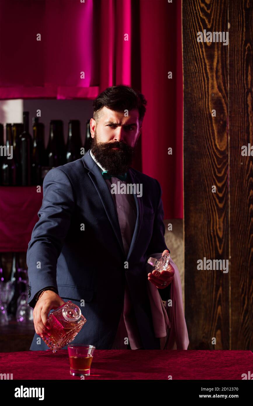 Barman che versa il brandy in un bicchiere di whisky. Bar uomo con brandy o cognac. Foto Stock