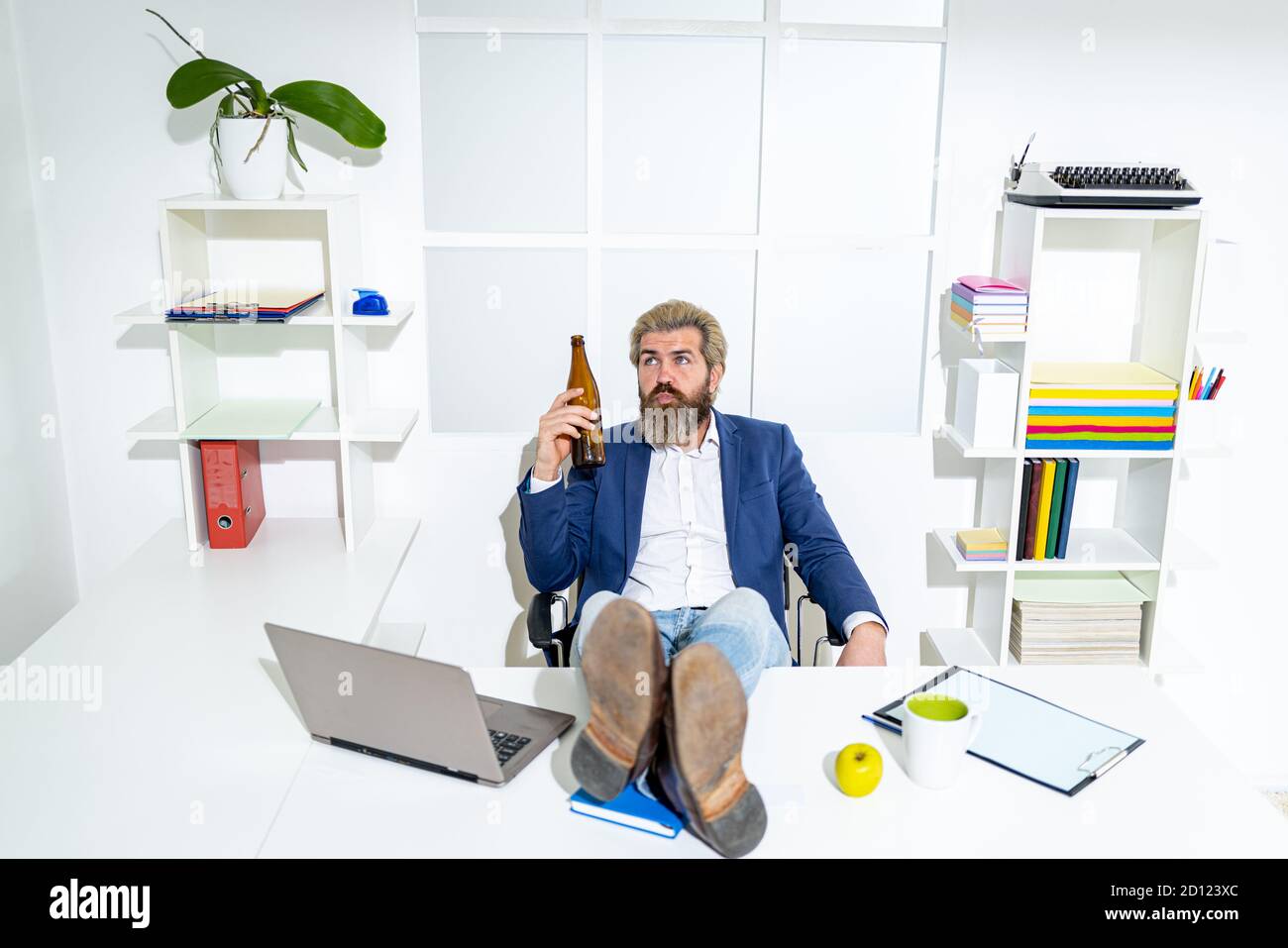 Triste lavoratore d'ufficio disperato sul licenziamento ingiusto perdere lavoro. Dopo un duro lavoro. Un uomo d'affari può tenere una bottiglia di birra. Foto Stock