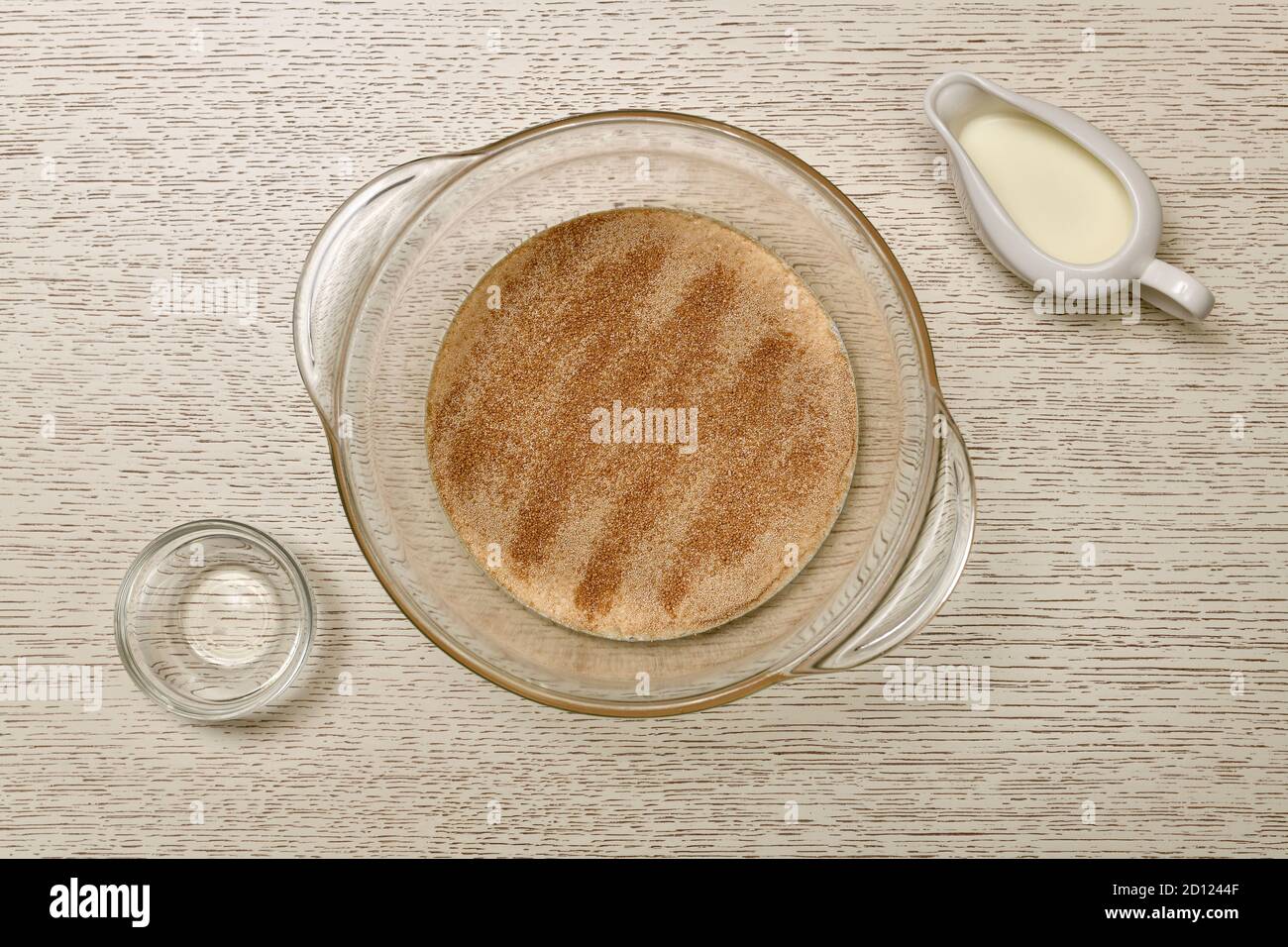 La fase di preparazione di un lotto di impasto di lievito. Sciogliere il lievito in un recipiente profondo trasparente con latte. Foto Stock