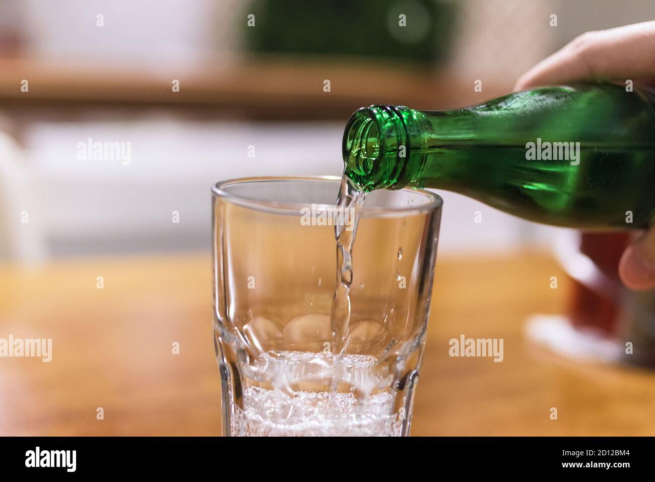 Le donne versano acqua minerale nel bicchiere del ristorante Foto Stock