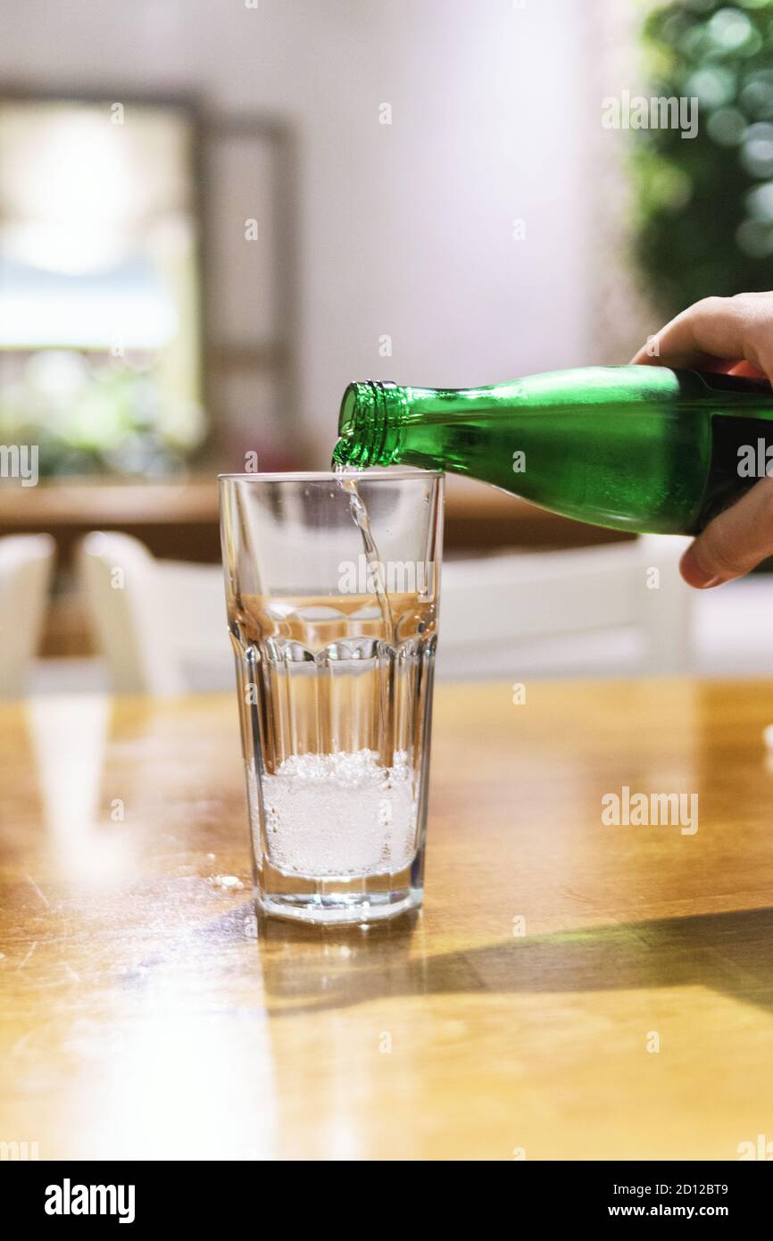 Le donne versano acqua minerale nel bicchiere del ristorante Foto Stock
