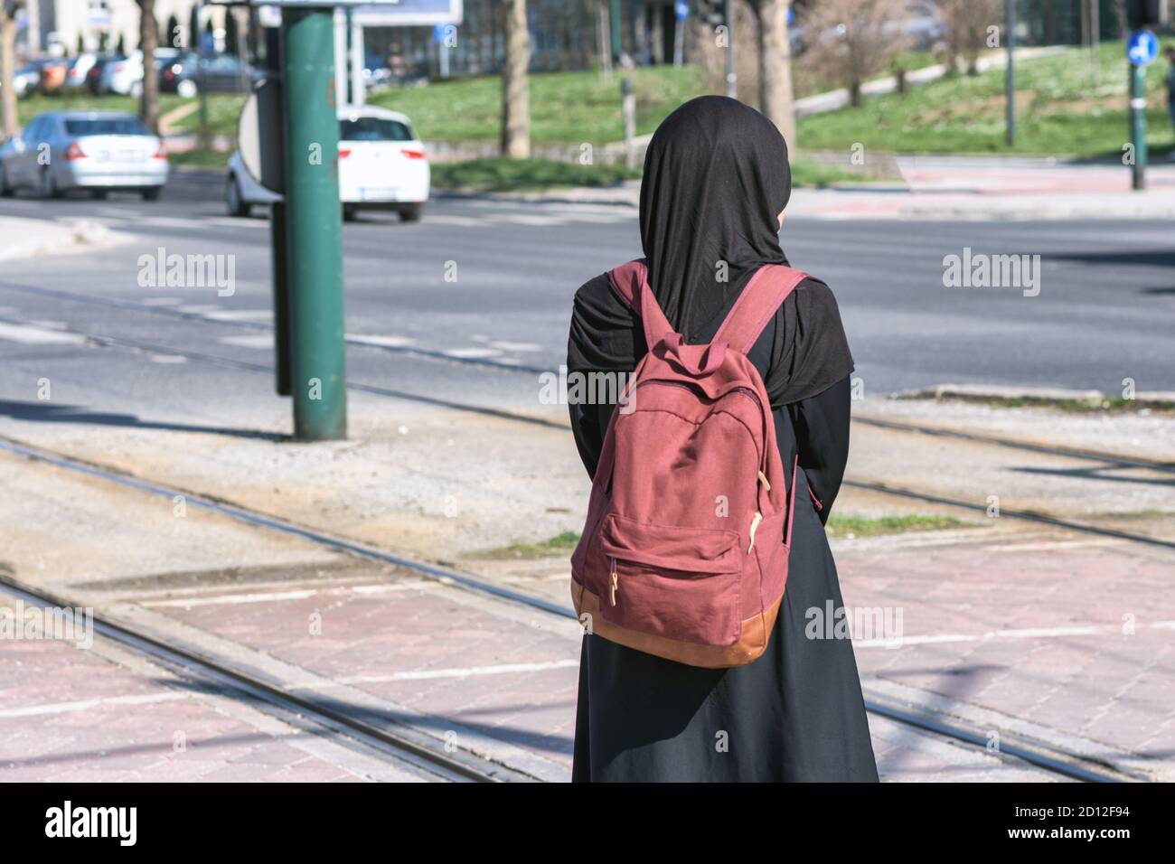 Donna musulmana in attesa di un tram alla stazione del tram Foto Stock