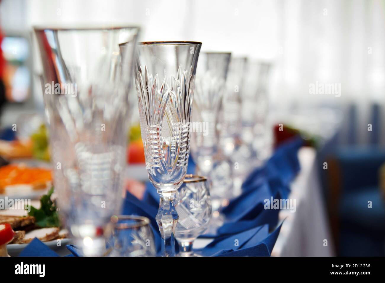 tavolo per banchetti servito con strumenti e decorato con file di bicchieri da vino vuoti Foto Stock